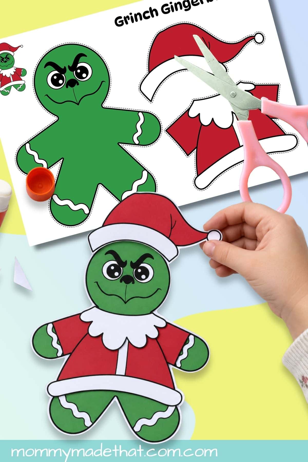 Child placing a Santa hat on a Grinch gingerbread man craft beside the printable template.