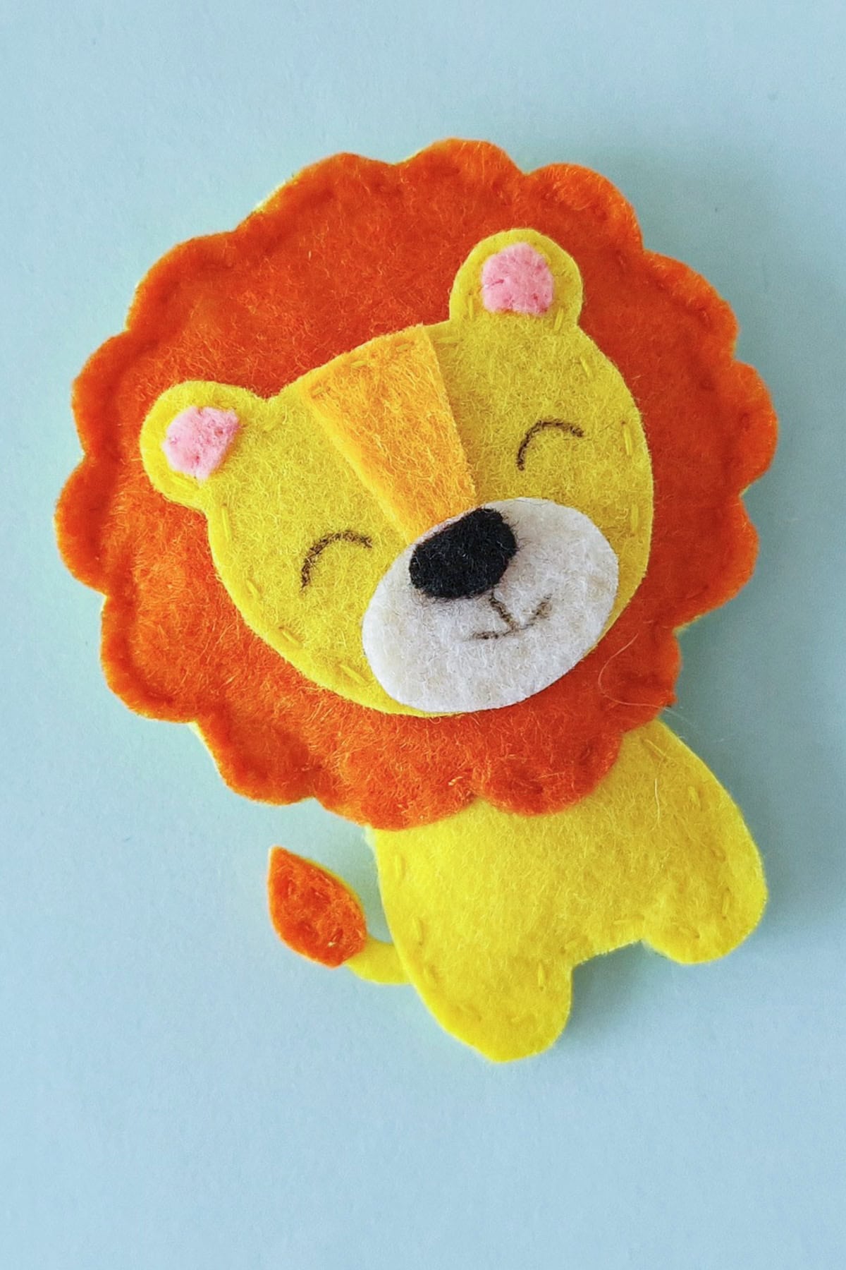 Close view of the finished felt lion plush with orange mane and smiling face