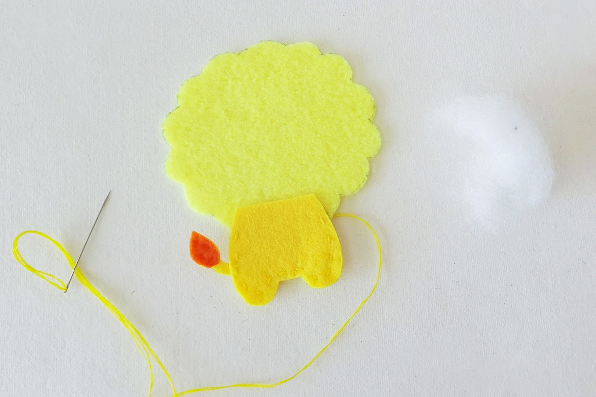 Stitching the yellow felt lower body onto the lion base