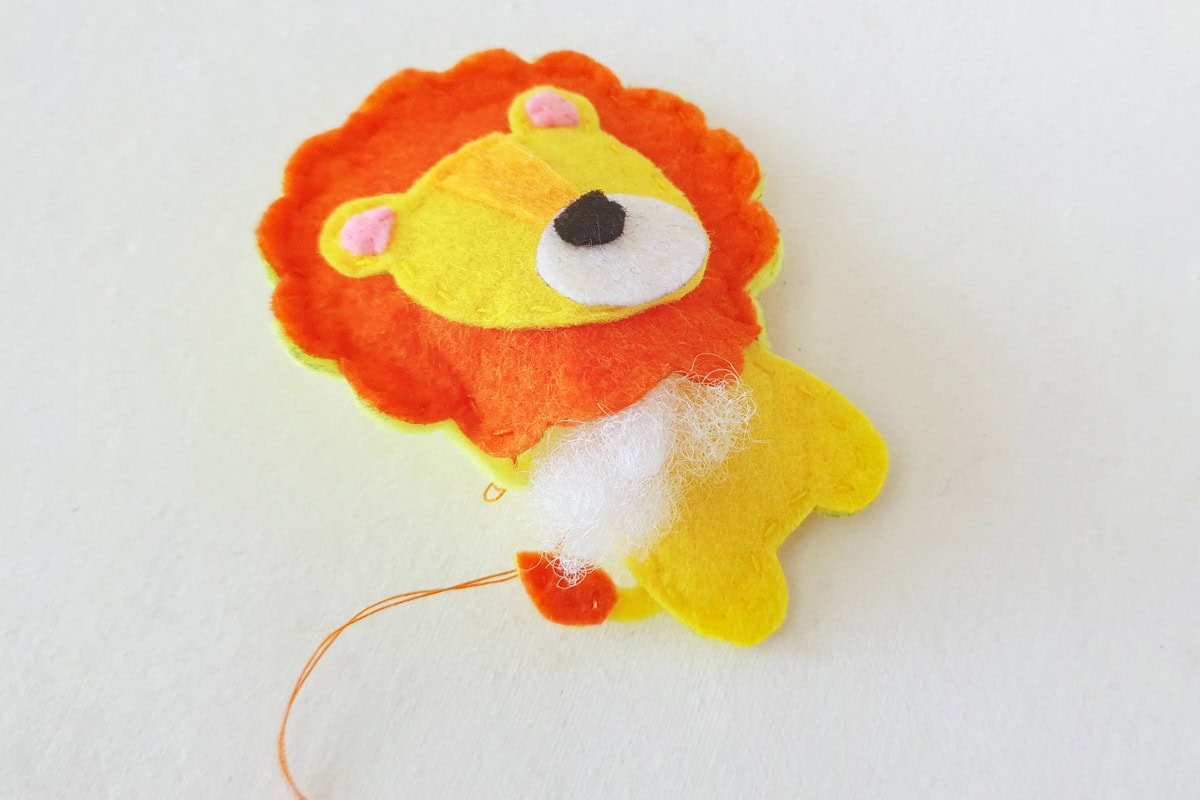 Cotton stuffing being added inside the lion’s orange mane and head