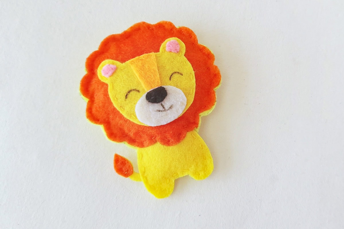 Completed felt lion plush with stitched mane and drawn eyes and smile