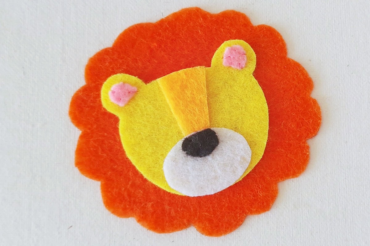 Yellow lion face centered on the orange felt mane