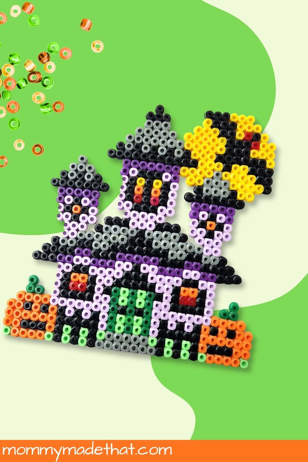 Finished purple haunted house made from fuse beads with orange pumpkins and a green doorway