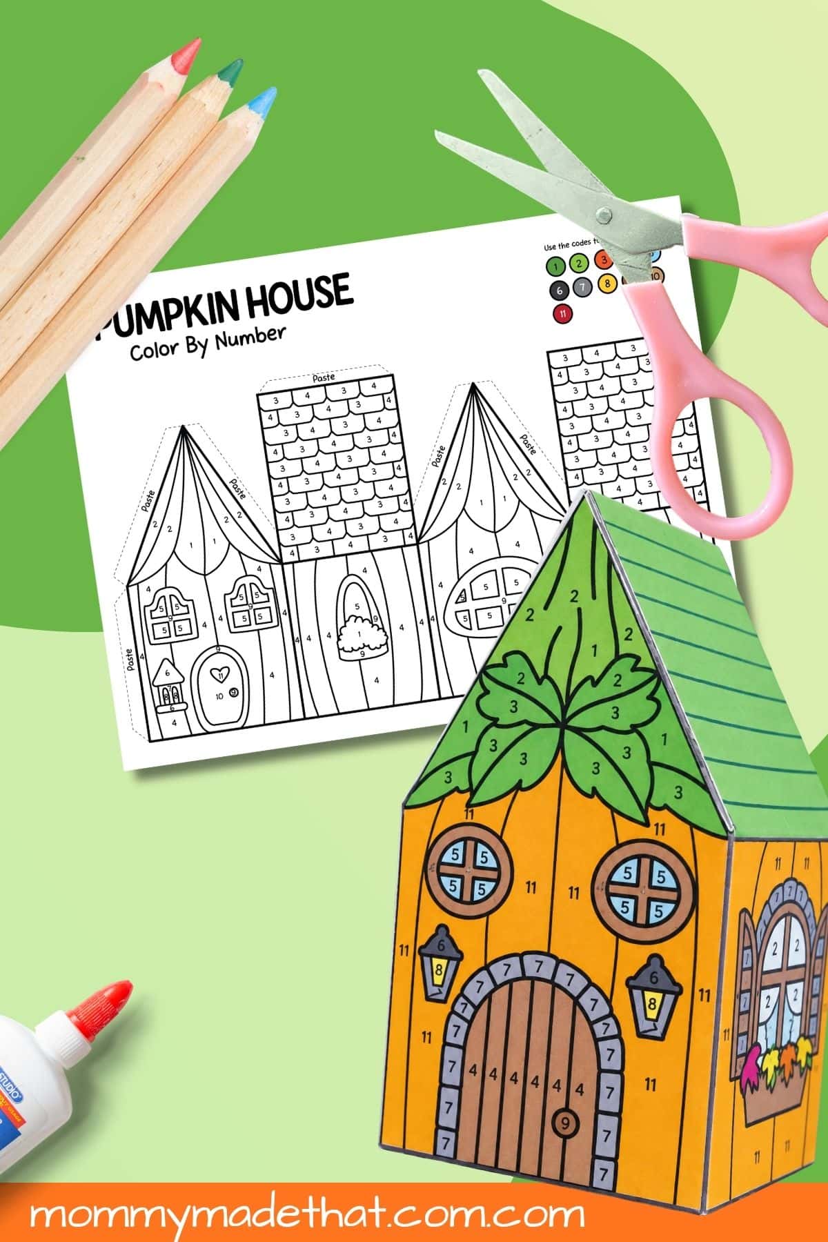 Assembled orange pumpkin house with a green roof beside a color-by-number template and craft supplies.