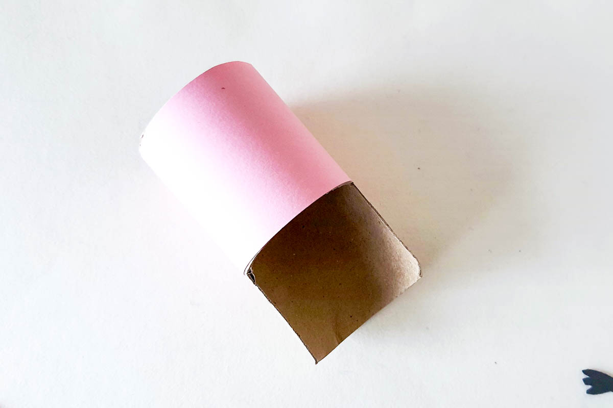 covering toilet paper roll with pink paper.